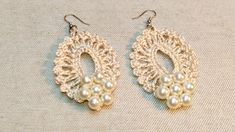 two pairs of earrings with pearls hanging from the end of each earring, on top of a beige cloth