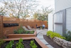 a man sitting on a bench in the middle of a garden next to a building