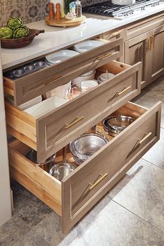 an open drawer in a kitchen with pots and pans on the counter top,