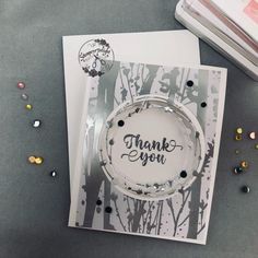 a thank you card with some confetti on the table next to it,