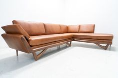 a brown leather couch sitting on top of a white floor next to a wooden frame