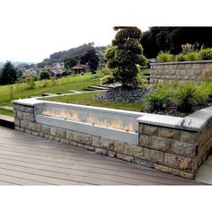 a fire pit sitting on top of a wooden deck next to a lush green hillside