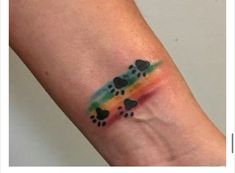 a small tattoo on the arm of a person with a rainbow dog paw and hearts