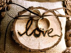 wedding rings are placed on top of a piece of wood with the word love written on it