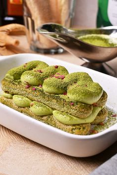 a white dish filled with green desserts on top of a wooden table