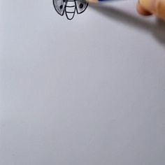 someone is drawing a bee on a piece of paper with a blue pencil and eraser