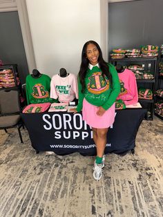 a woman standing in front of a table with shirts on it