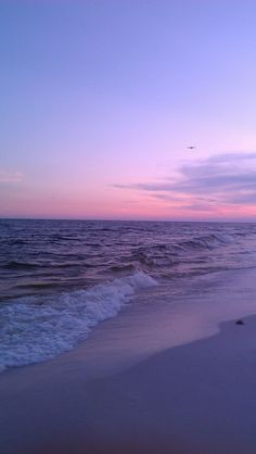 an airplane flying over the ocean at sunset