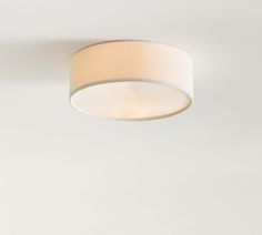 a white ceiling light with a round shade on it's side, against a plain wall