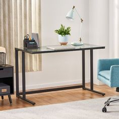 a desk with a chair, lamp and plant on it in front of a window