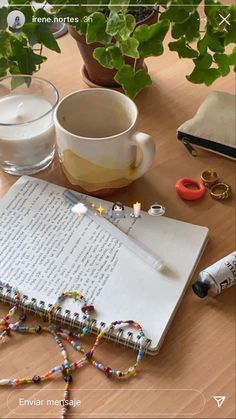 an open book sitting on top of a wooden table next to a cup and other items