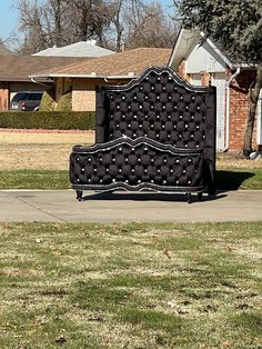 a black bed sitting on top of a lush green field next to a house in the background