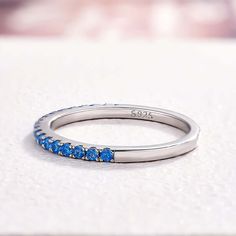 a white gold ring with blue stones on the side, sitting on top of a table