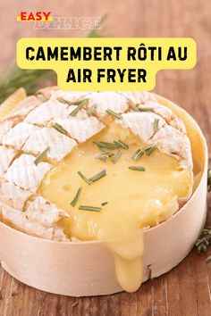 a wooden bowl filled with cheese and crackers on top of a wooden table next to herbs