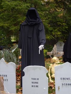 three tombstones decorated with skeletons and grime clothing, one wearing a black robe