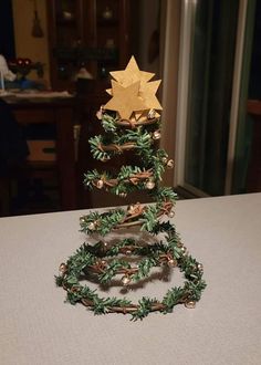 a christmas tree made out of branches and pine cones with gold stars on top, sitting on a table