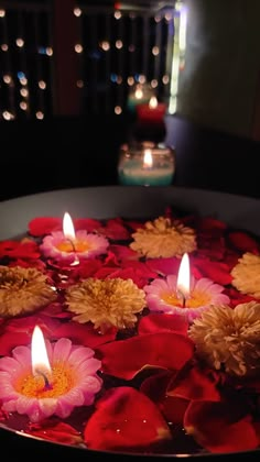 flowers floating in water with candles on the side