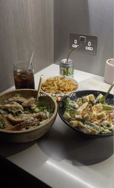 two bowls filled with food sitting on top of a counter next to a bowl of fries