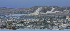 a snowboarder is going down a hill in front of a town and ski lift