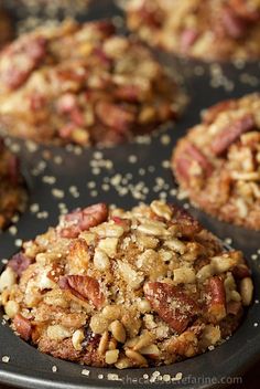 a muffin with nuts and other toppings sitting on a baking sheet, ready to be eaten