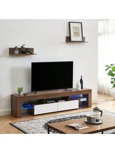 a living room with a large tv on top of a wooden shelf next to a coffee table