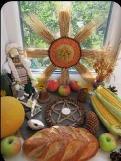 a table topped with bread, apples and corn on top of a window sill