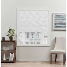 a living room with a chair and window covered in white roman blind shades on the windowsill