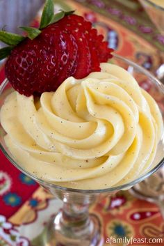 two strawberries sit on top of a dessert in a glass bowl