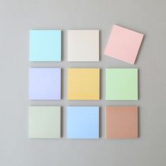 several different colors of sticky notes on a gray surface with one pink, one blue and one yellow