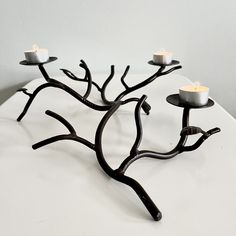 a group of candles sitting on top of a white table next to a tree branch