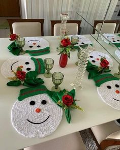 a white table topped with place mats covered in frosty snowman faces and red roses