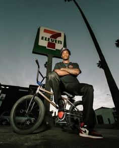 a man sitting on top of a bike next to a 7 eleven sign