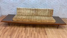 a couch sitting on top of a wooden floor next to a white brick wall in a room