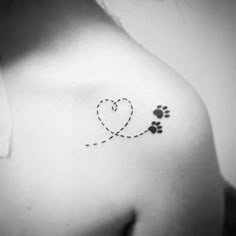 a black and white photo of a woman's back shoulder with a dog paw tattoo on it