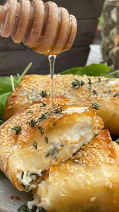 a plate topped with bread covered in cheese and greens next to a honey drizzle