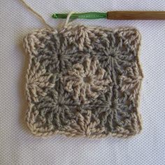 a crocheted square with a knitting needle