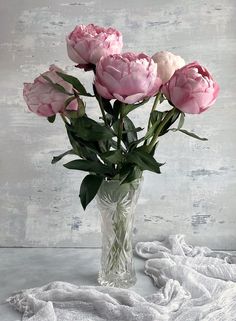 a vase filled with pink flowers sitting on top of a white cloth covered tablecloth