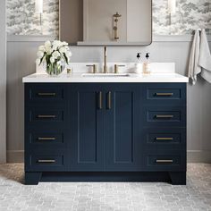 a bathroom vanity with two sinks, mirrors and flowers in vases on the counter