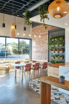 a restaurant with tables, chairs and plants hanging from the ceiling