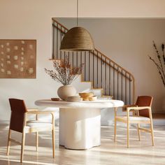 a dining room table with chairs and a vase on the table in front of it