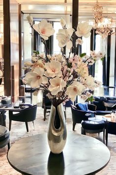 a vase filled with flowers sitting on top of a table in front of a chandelier