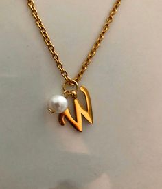 Letter W necklace, set on a stainless steel ,golden color chain. Chain length 19'  With addition cost there is an option to add a white freshwater pearl, as a charm, next to the letter. 6 mm, white round pearl Kindly choose your option. Beautiful spiritual gift. Please make sure you to pay attention to the size of the pendant. I have added pictures next to 25 cent coin, and measurement tape.  Need a different length just write it to me in the "message to the seller" box of the order form. **LIMI Minimalist White Initial Necklace For Personalized Gift, Minimalist White Charm Necklace For Personalized Gift, Minimalist White Initial Necklace For Anniversary, Elegant Initials Necklace In Stainless Steel, Elegant Initials Stainless Steel Necklace, Dainty Charm Necklaces With Pearl Initial Pendant, Elegant Stainless Steel Initials Necklace, Elegant Hypoallergenic Initial Pendant Charm Necklace, Elegant Hypoallergenic Charm Necklace With Initial Pendant