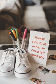 a pair of white tennis shoes sitting on top of a table next to a sign