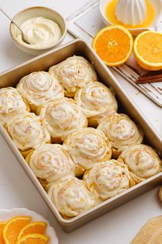 a pan filled with orange meringue rolls next to sliced oranges