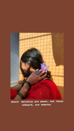 a woman in red shirt holding a purple flower next to her face with words on it