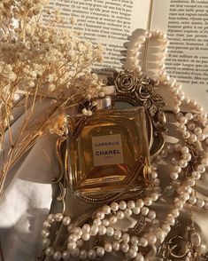 a bottle of chanel perfume sitting on top of a table next to pearls and flowers