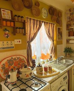 a stove top oven sitting inside of a kitchen next to a window with curtains on it