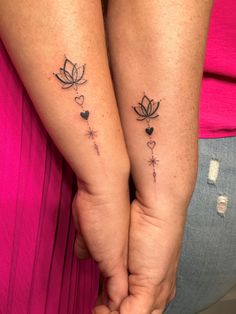 two people holding hands with tattoos on their arms and one has a heart shaped flower