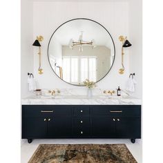 a bathroom vanity with two sinks and a large round mirror above it, along with a rug on the floor