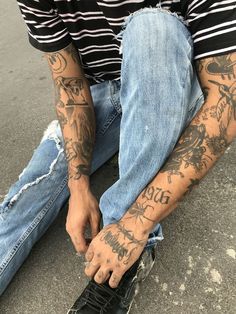 a man with tattoos sitting on the ground